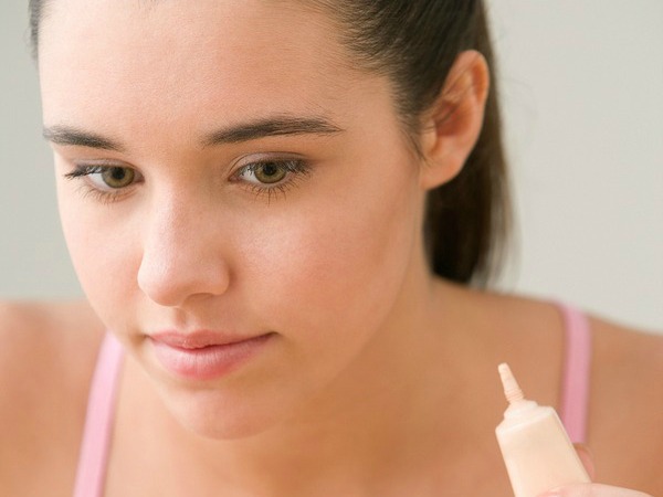 Teenage girl looking in mirror and holding cover up